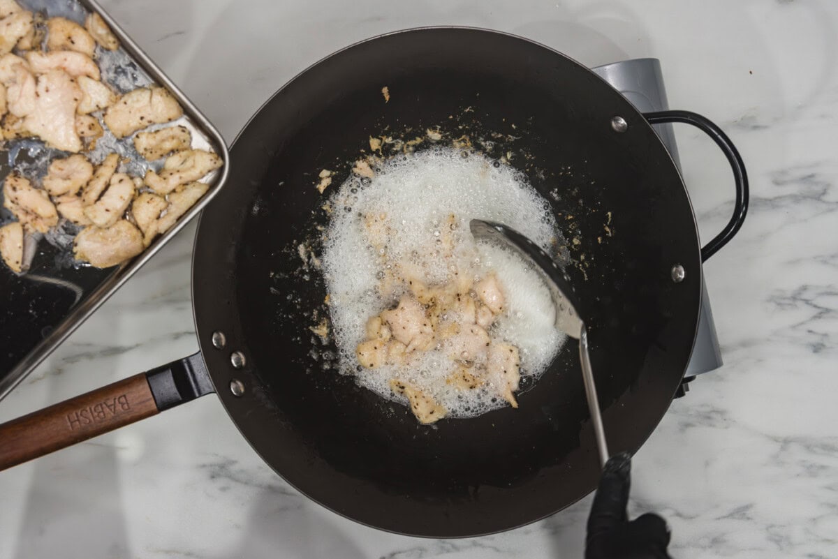 removing chicken from wok of oil with a spoon