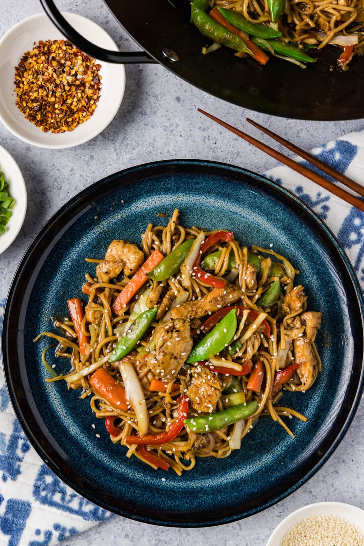 Plate of Chicken Lo Mein with a wok behind it