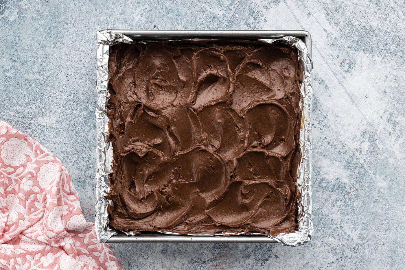 Fudge frosted on top of espresso brownies in a baking pan