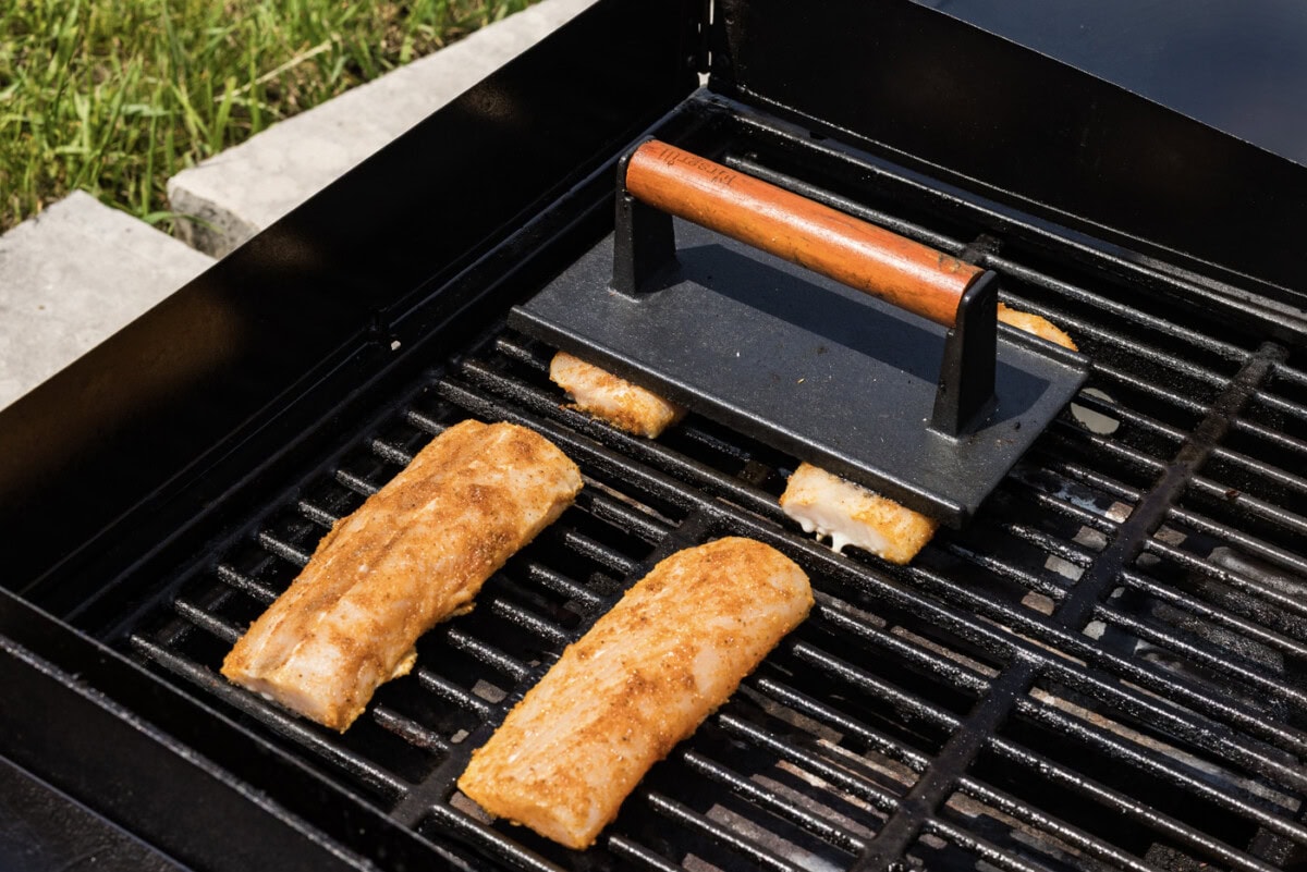hamburger press over mahi mahi filets on a grill
