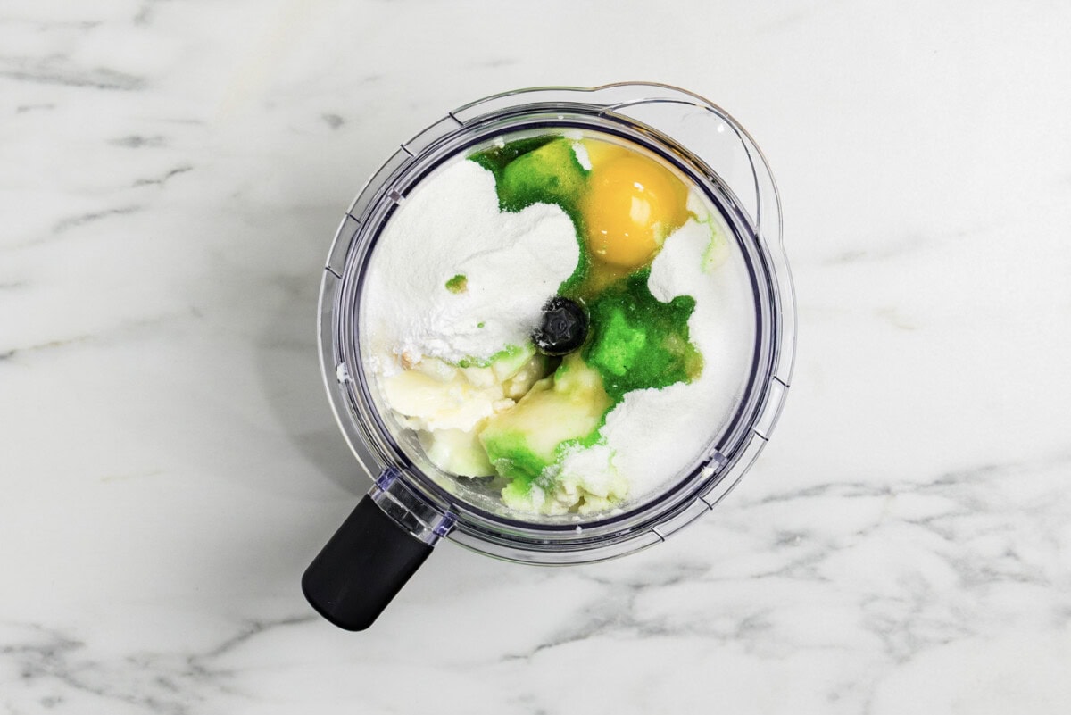 overhead photo of keto lime cheesecake ingredients in a food processor bowl