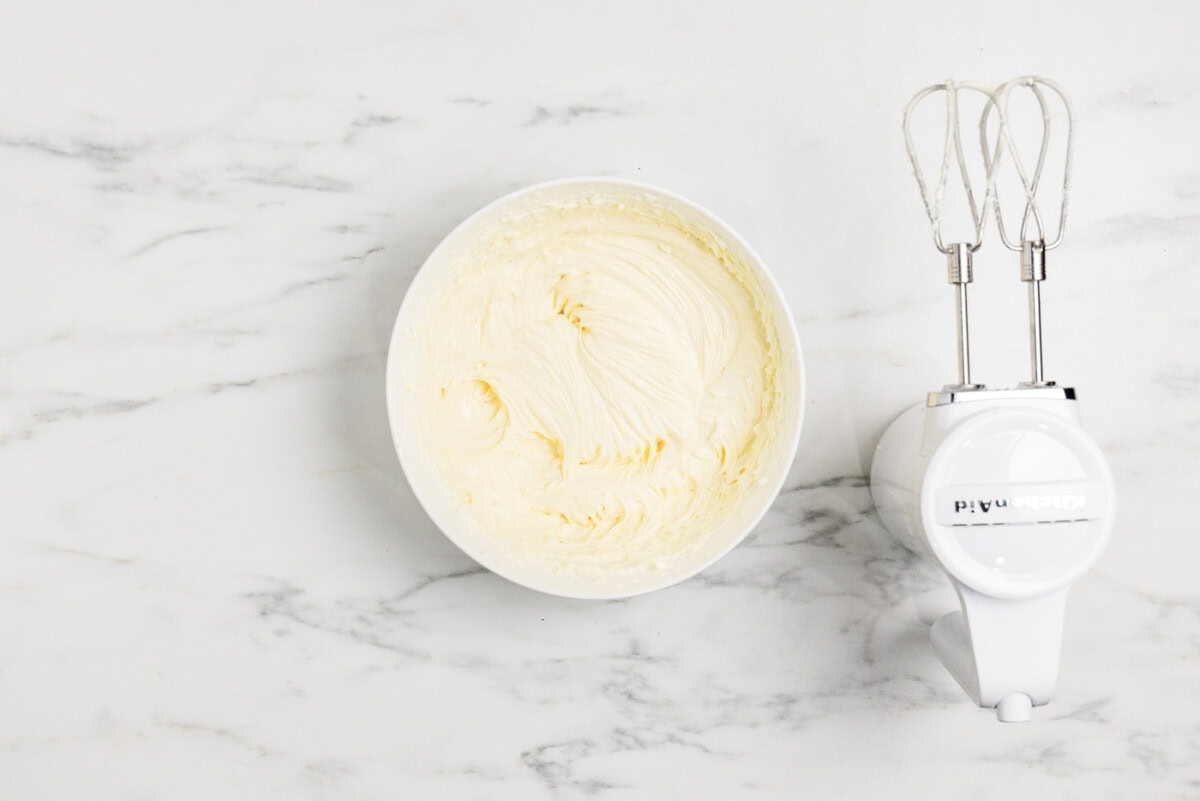 cheesecake batter in a bowl next to an electric mixer
