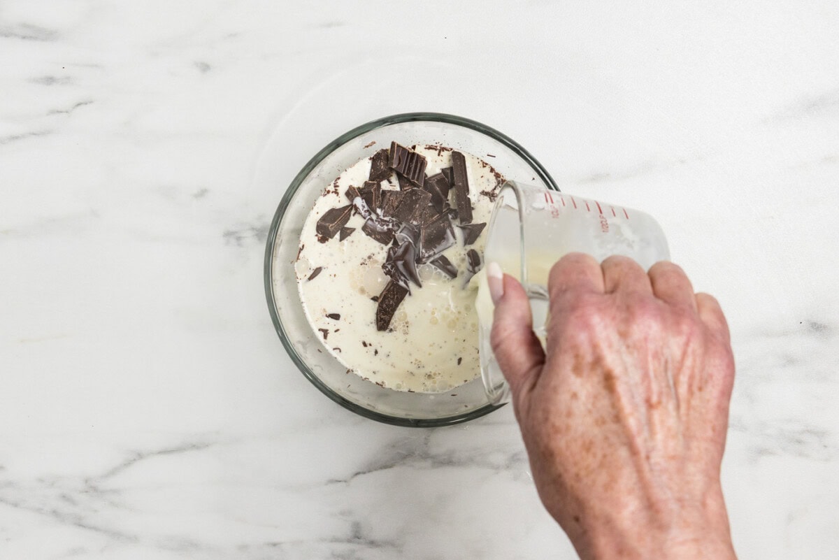 pouring hot cream over chopped chocolate in a bowl
