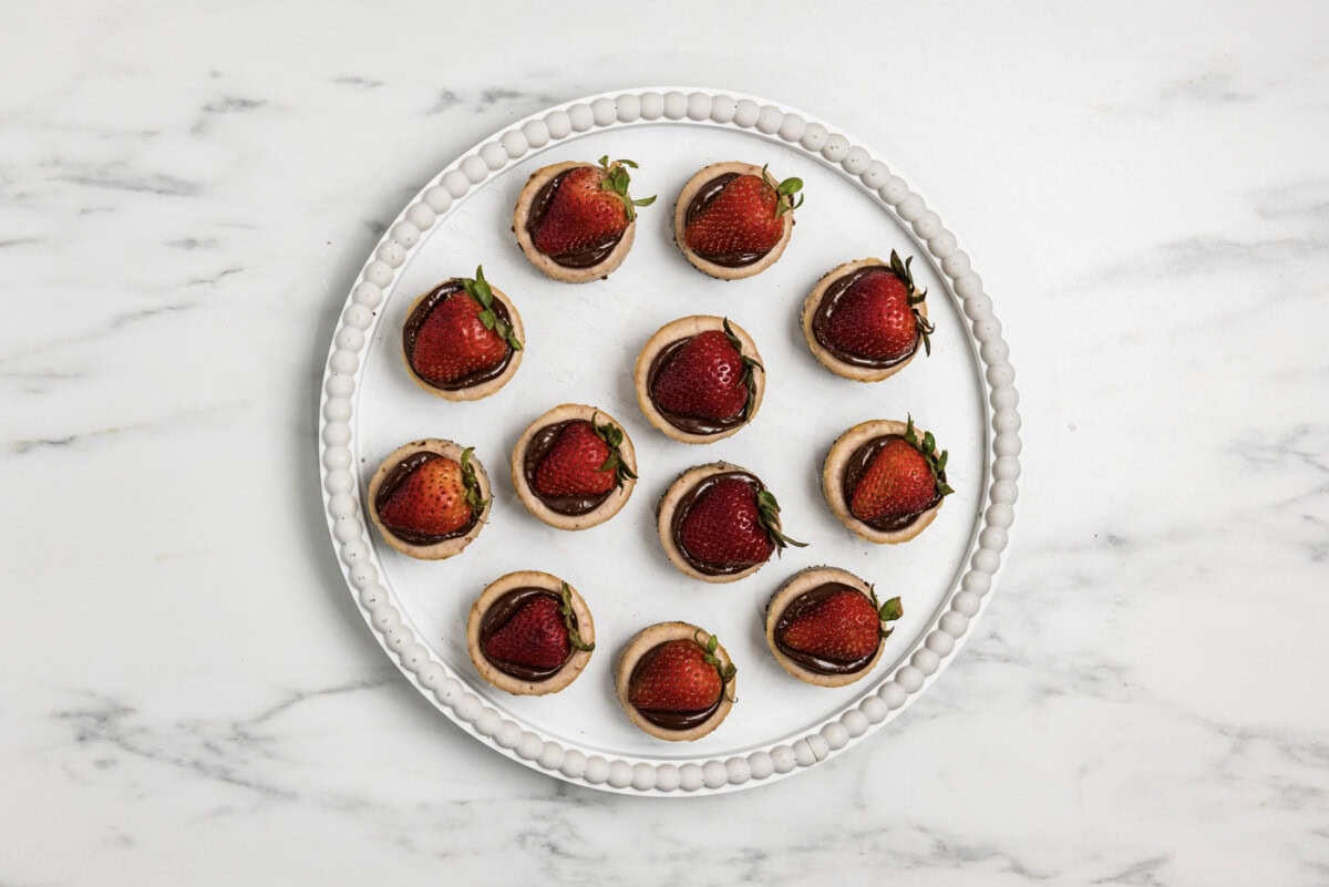 overhead of mini strawberry cheesecakes topped with ganache and strawberries