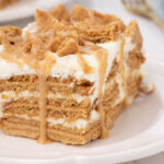 slice of nutter butter icebox cake with peanut butter drizzle on white plate