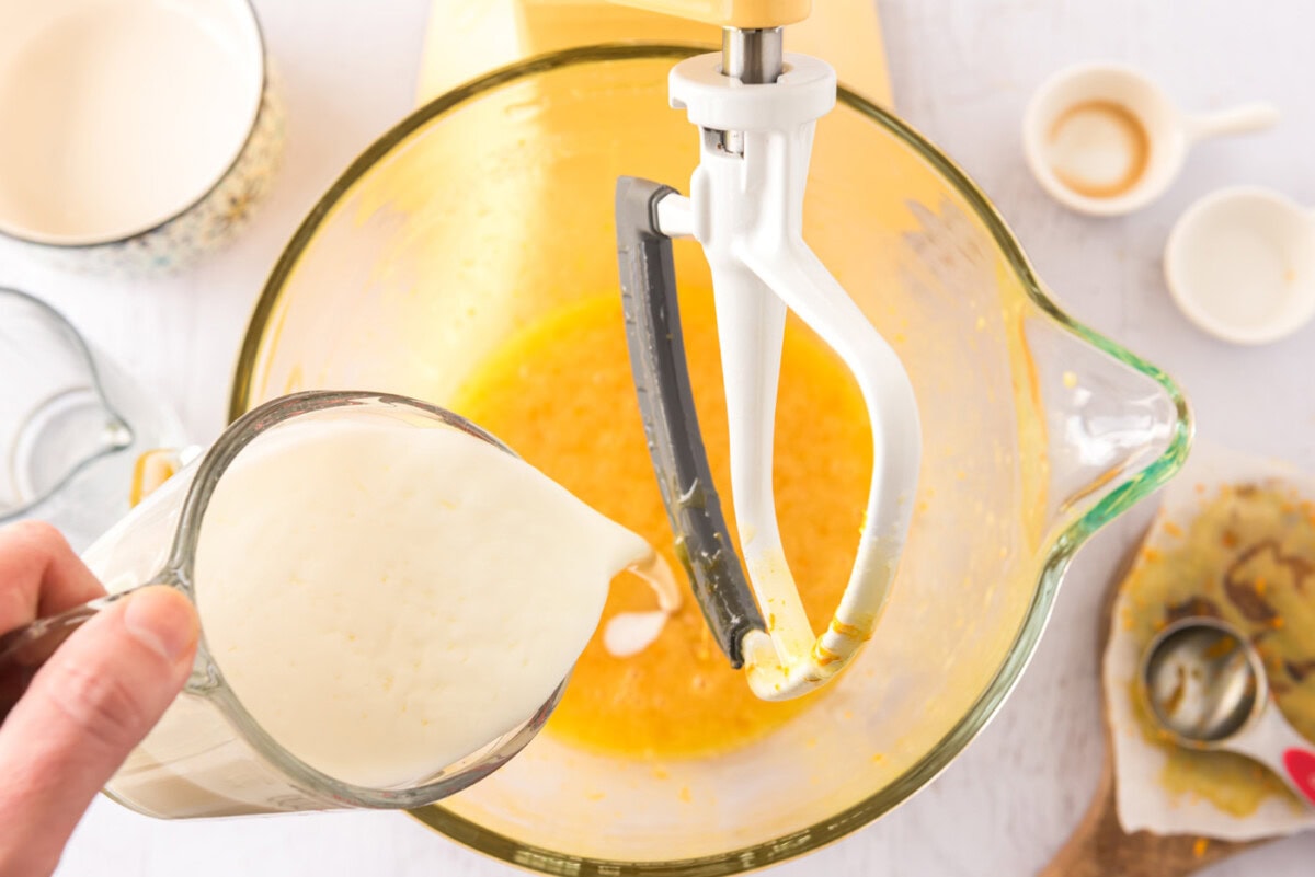 pouring buttermilk into orange egg mixture in a stand mixer