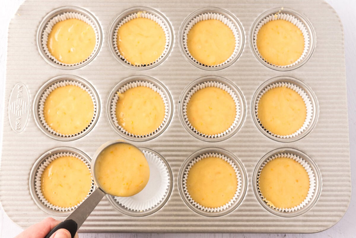 spooning cupcake batter into a pan