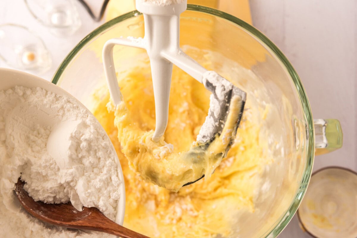 adding confectioners' sugar to bowl with cream cheese mixture
