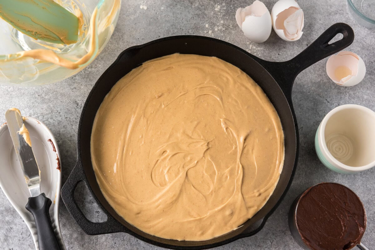 peanut butter cream cheese mixture added on top of brownie batter in a skillet