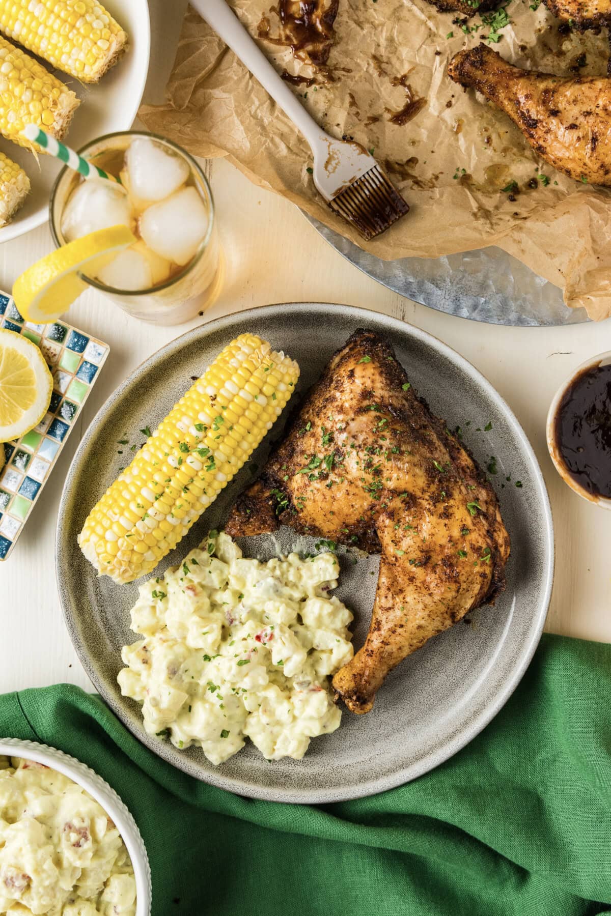 Smoked Chicken Quarter on a plate with potato salad and corn on the cob