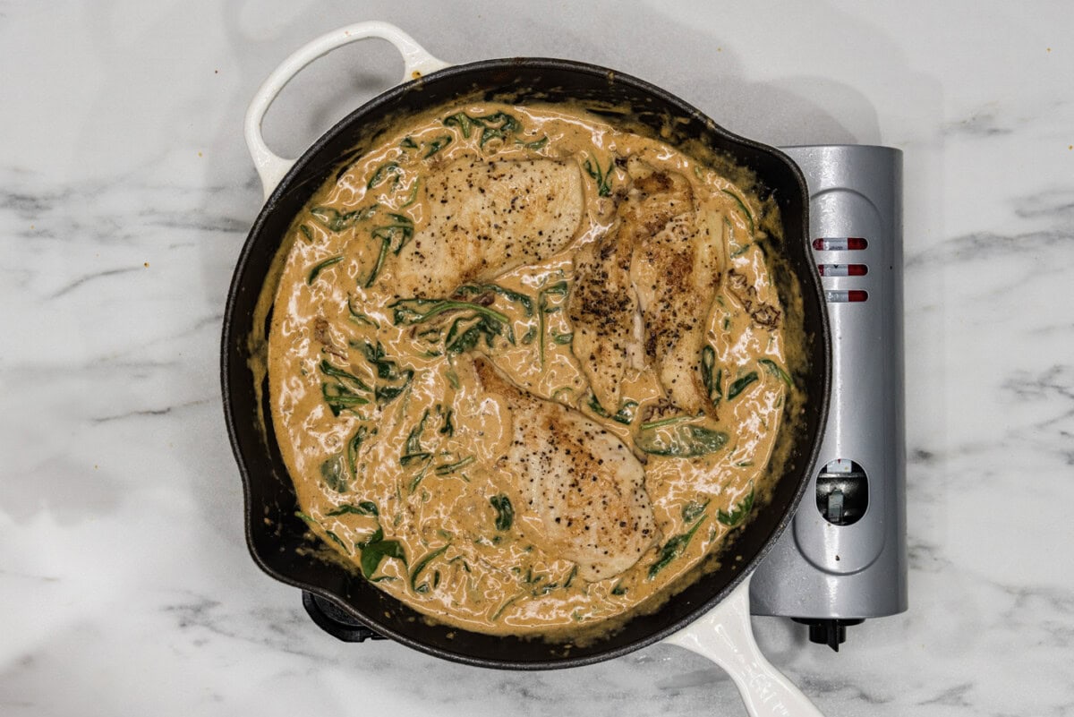chicken breasts in a skillet with tuscan sauce