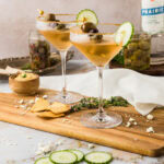 Two Dirty Greek Martinis on a wooden platter