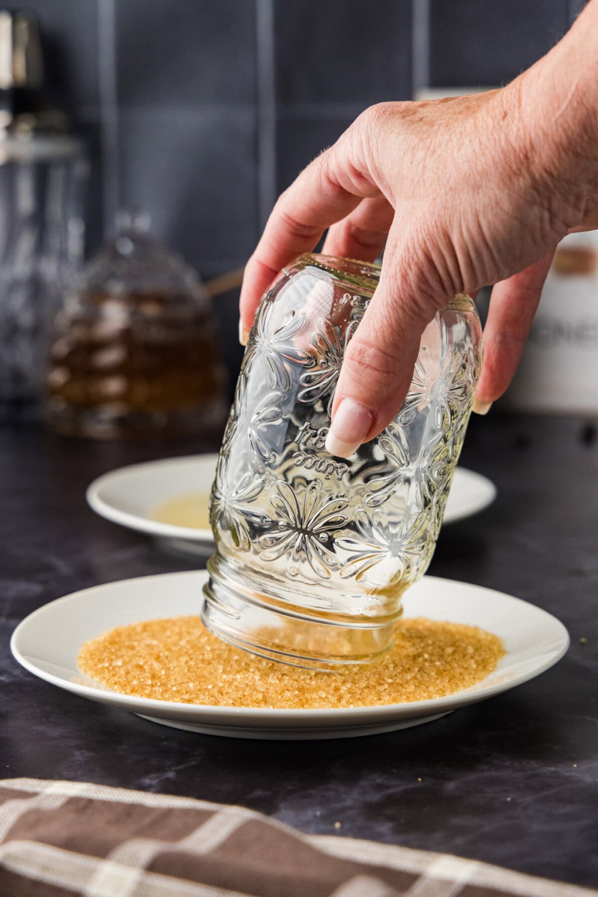 hand dipping drinking glass into turbinado sugar