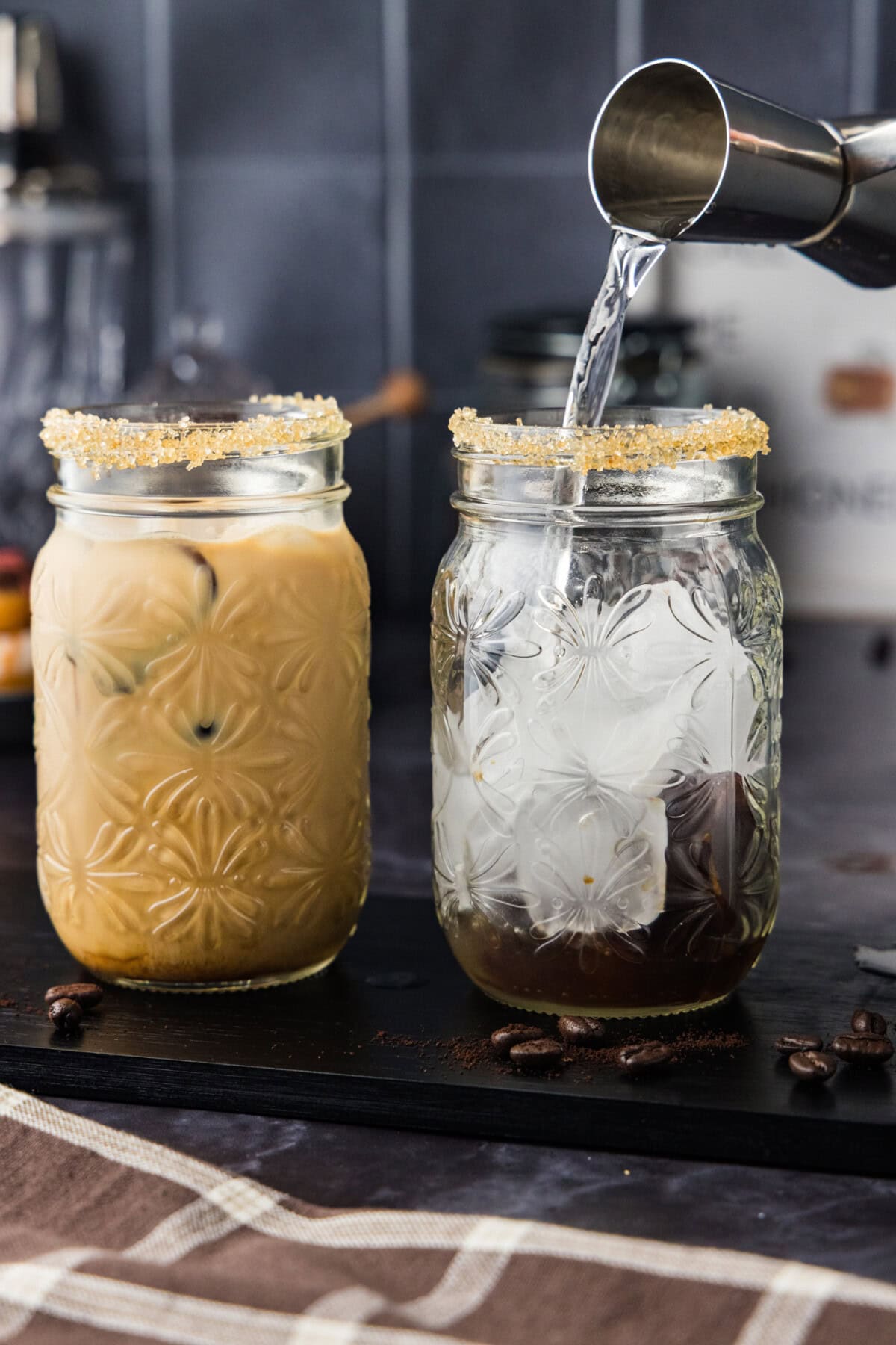 pouring vodka from jigger into a glass with ice