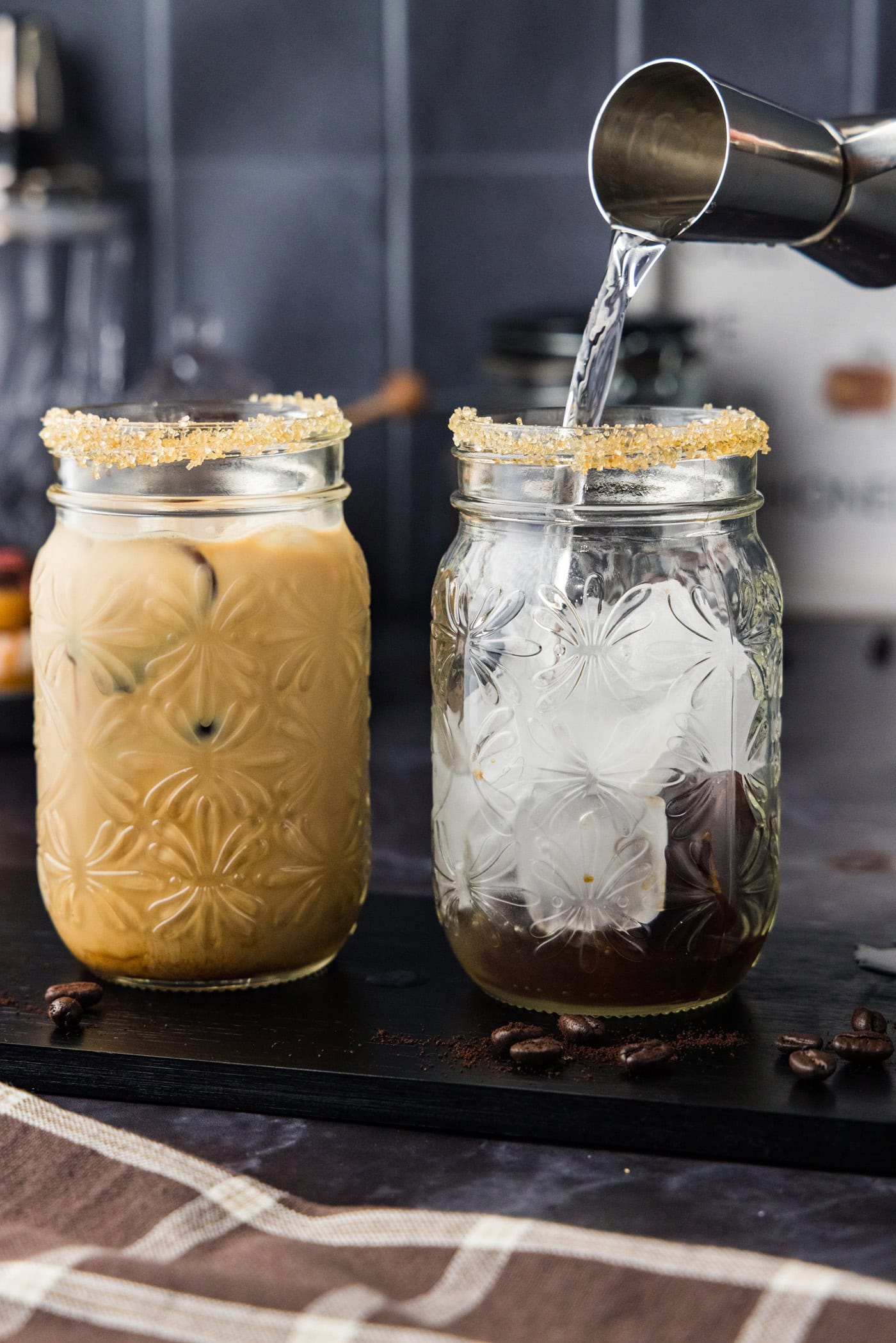 pouring vodka from jigger into a glass with ice