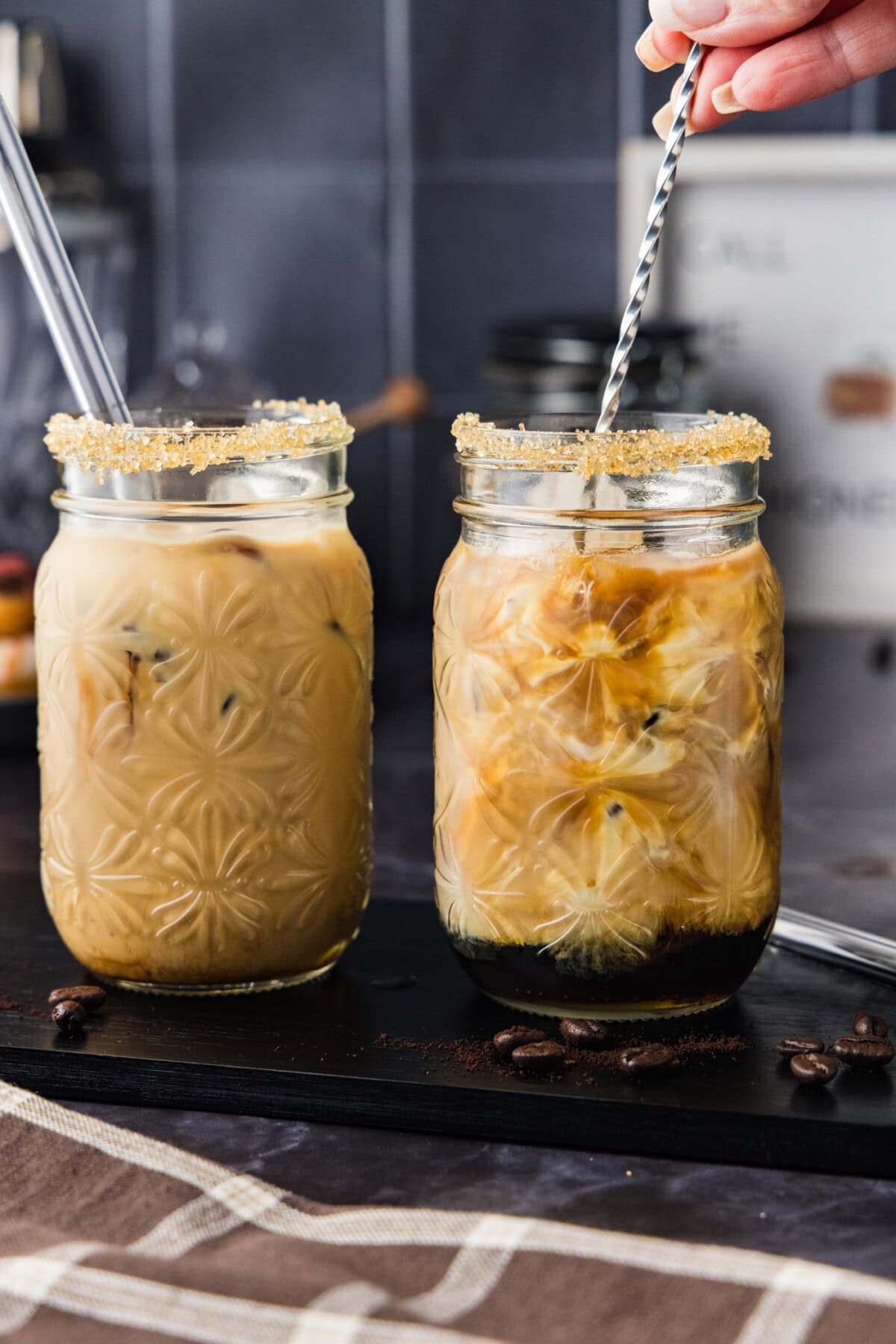 Hand using a cocktail stirrer to mix iced espresso cocktail together in a glass