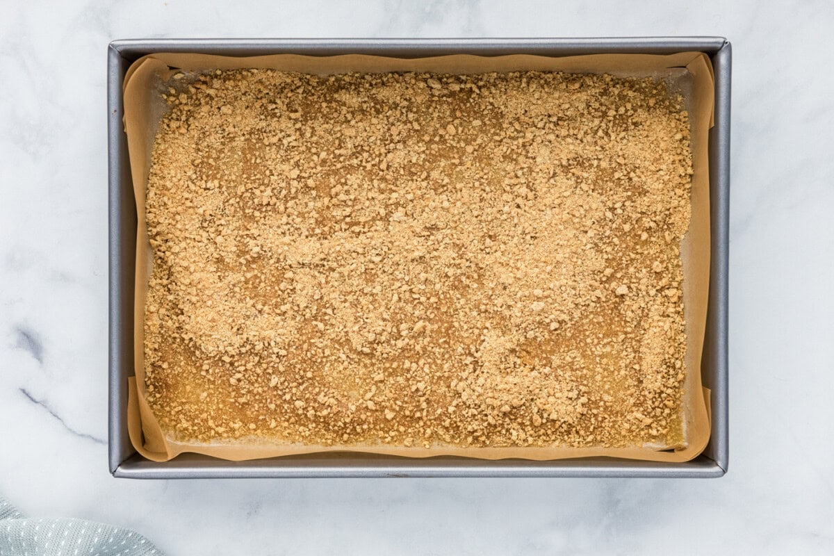 graham cracker crumbs sprinkled over melted butter in a baking pan