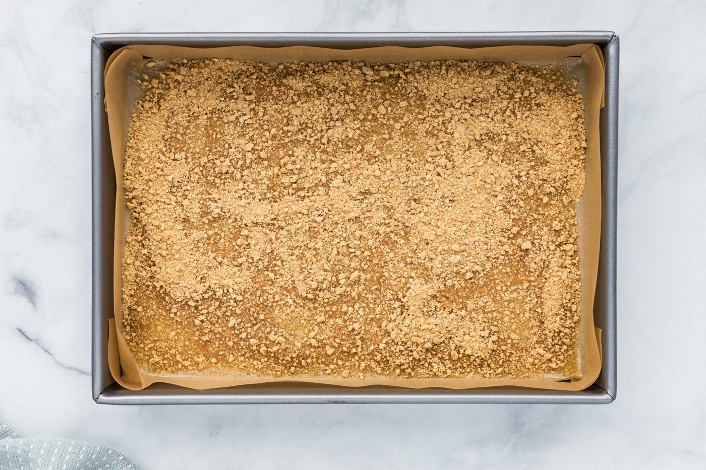 graham cracker crumbs sprinkled over melted butter in a baking pan