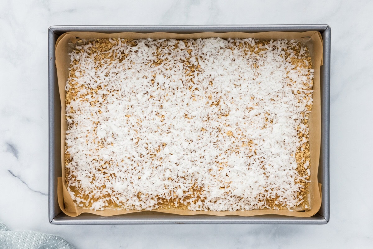 shredded coconut sprinkled over graham crumbs and melted butter in a baking pan
