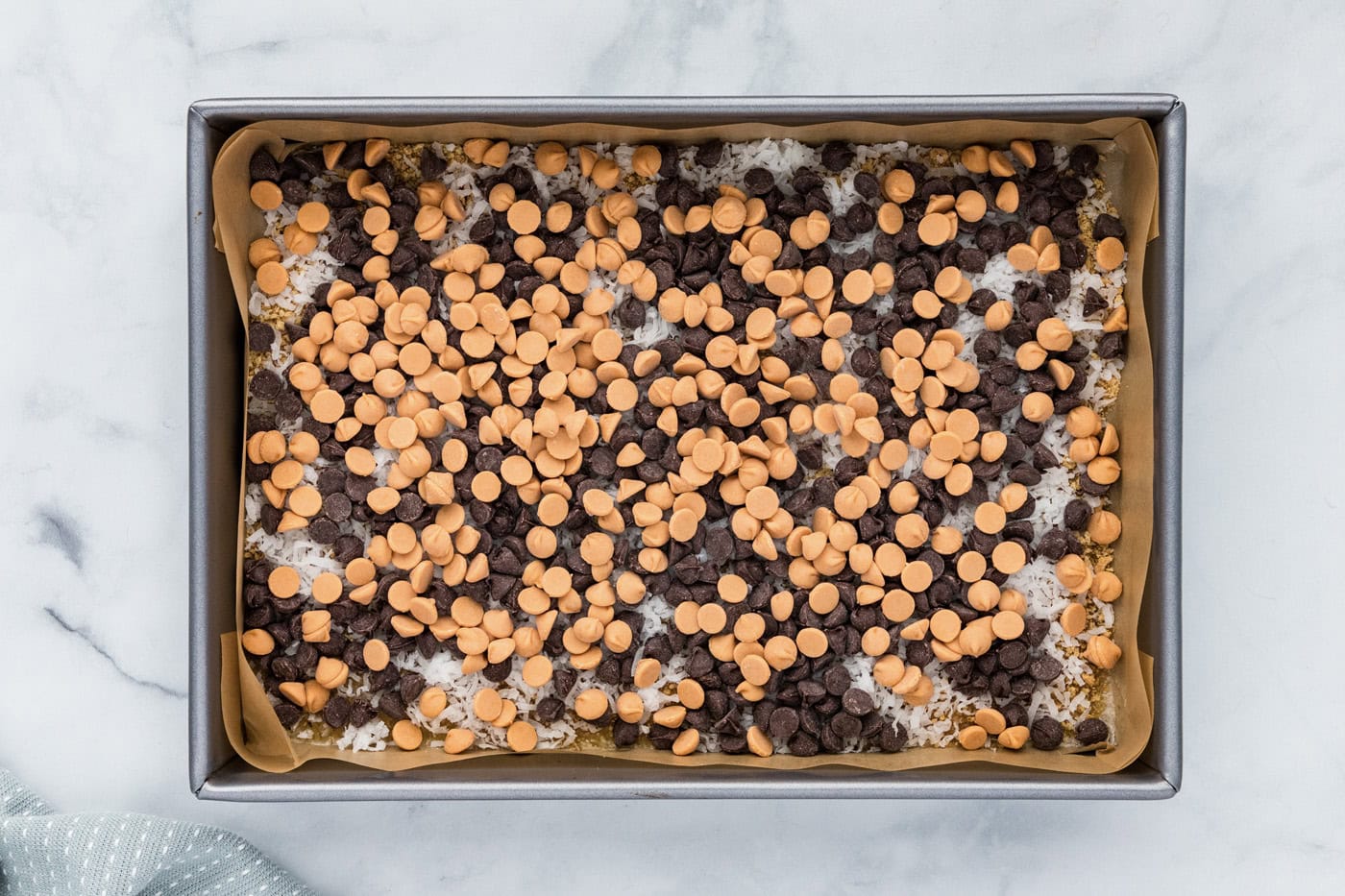 semi sweet and butterscotch chocolate chips over top of shredded coconut and butter layer