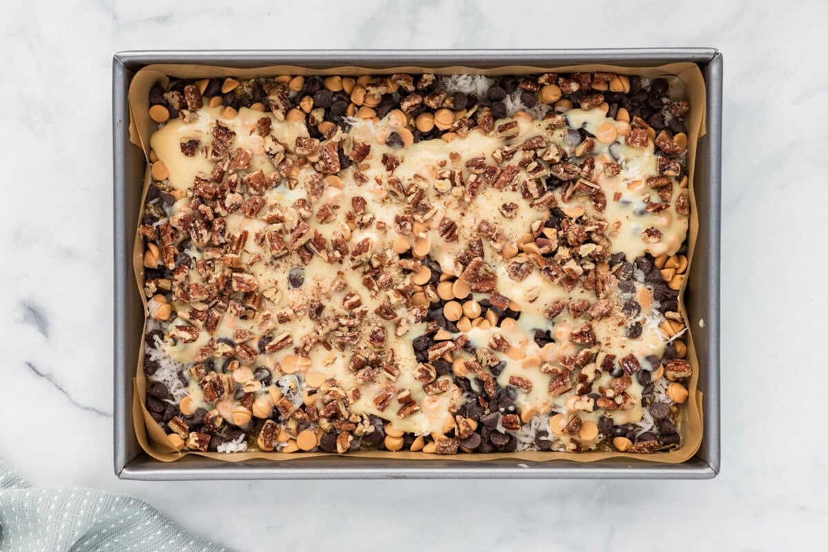 chopped pecans sprinkled over magic bars in a baking dish