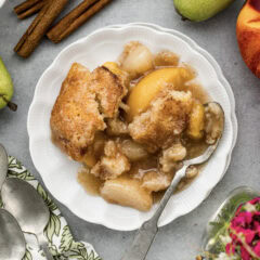 Close up photo of a plate of Pear-Peach Cobbler topped with a scoop of ice cream
