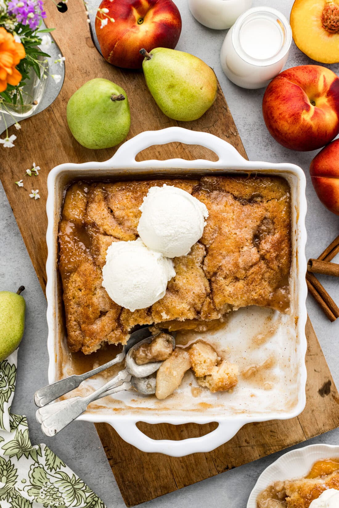 Baking dish of Pear-Peach Cobbler topped with two scoops of ice cream