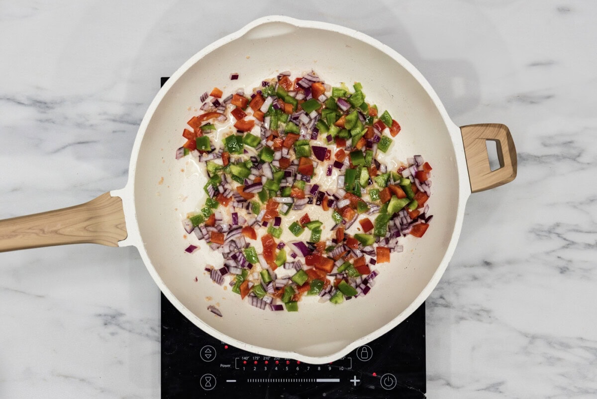 bell peppers, onion, and garlic sauteeing in a skillet