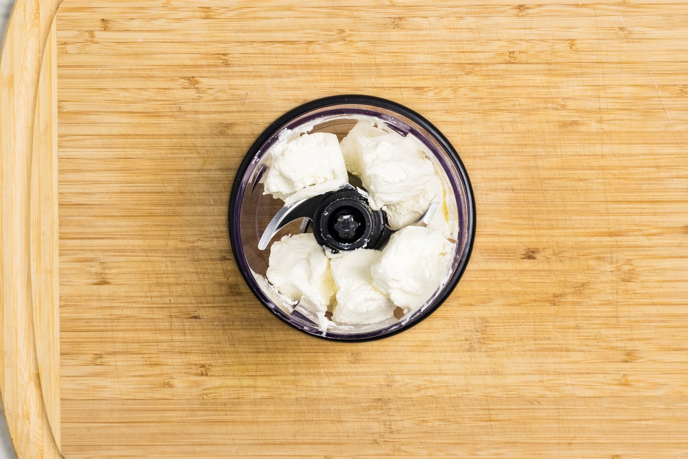 cubed cream cheese in the bowl of a mini food chopper