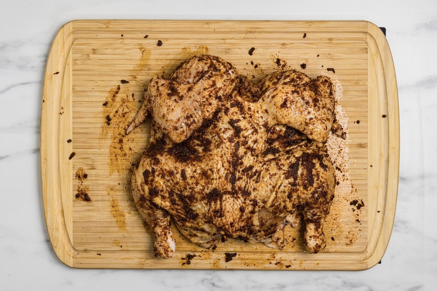 spices and seasonings rubbed on spatchcock chicken