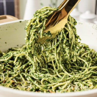 Close up photo of tongs holding up Spinach Spaghetti