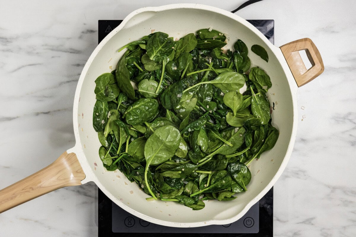 spinach leaves added to skillet with butter, garlic, and shallots