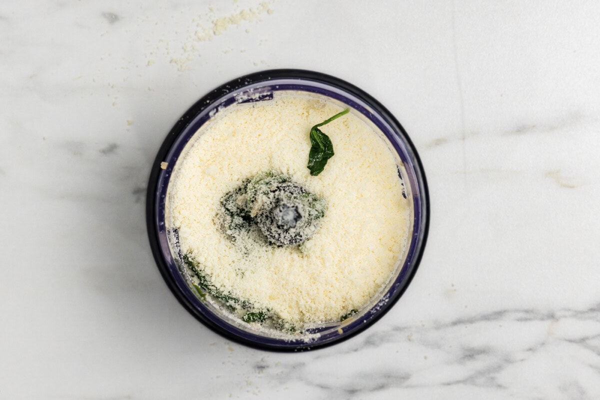 parmesan cheese added to spinach mixture in a food chopper