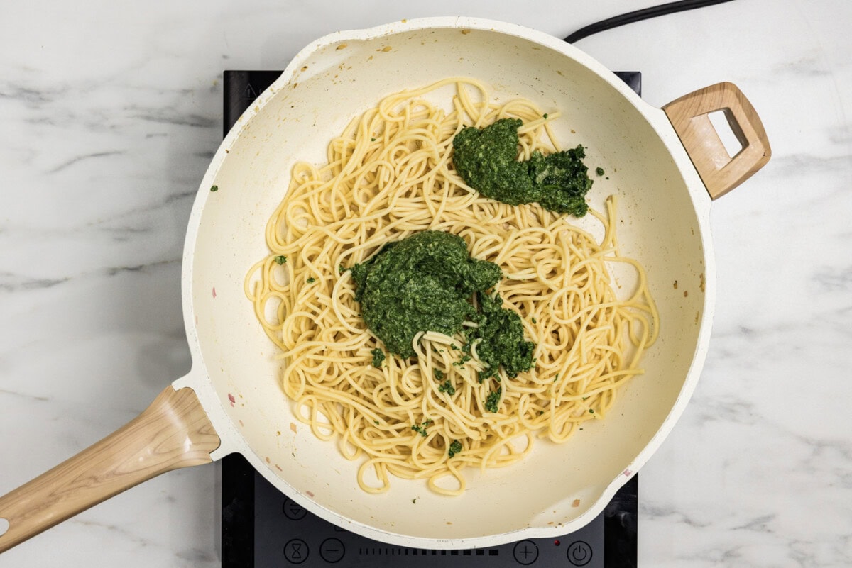 spinach sauce added to skillet with cooked spaghetti noodles