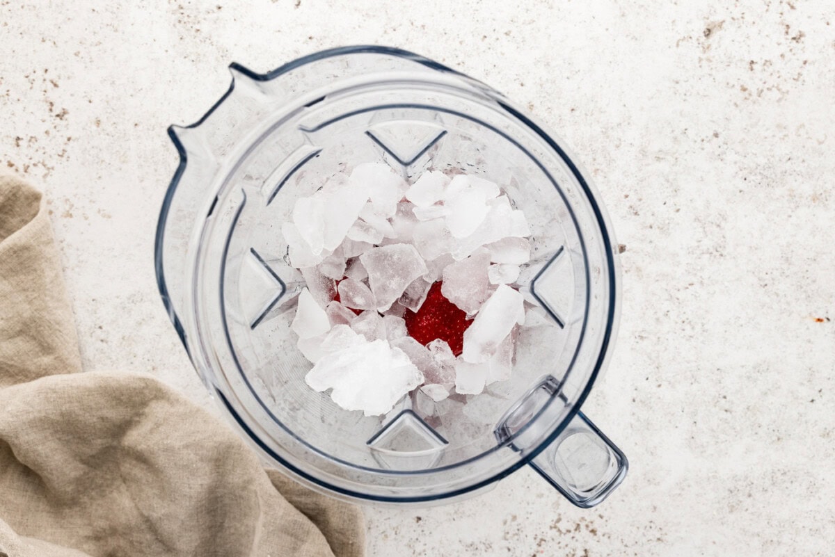 ice on top of strawberries in a blender