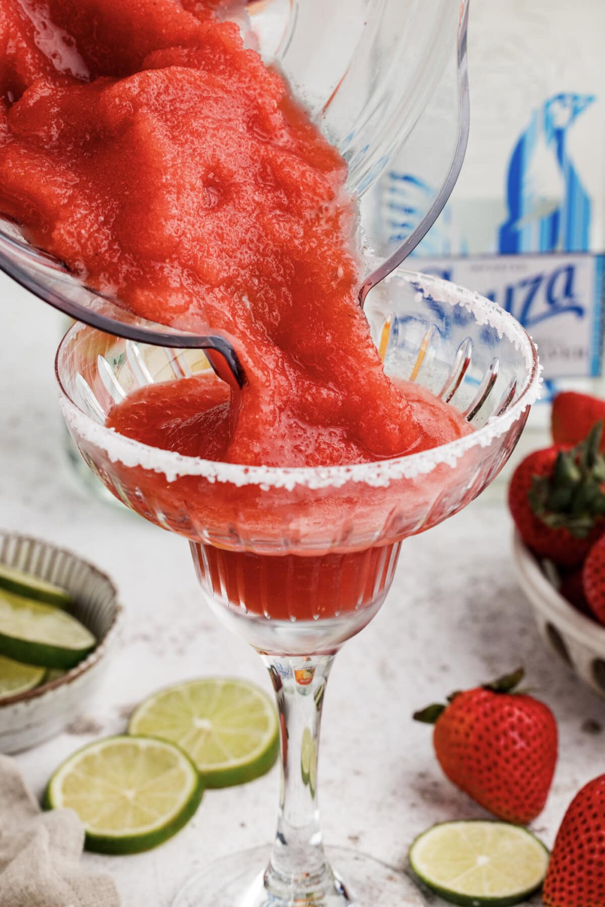 pouring strawberry margarita slush from blender into a glass