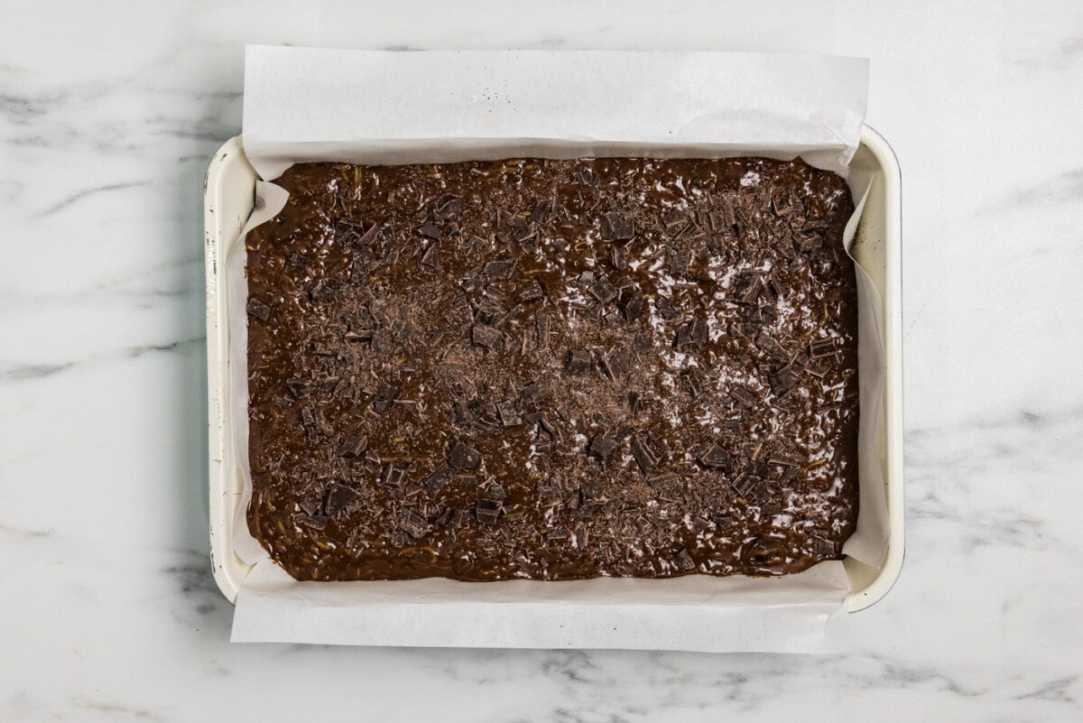 zucchini brownie batter in a pan with chopped chocolate sprinkled on top