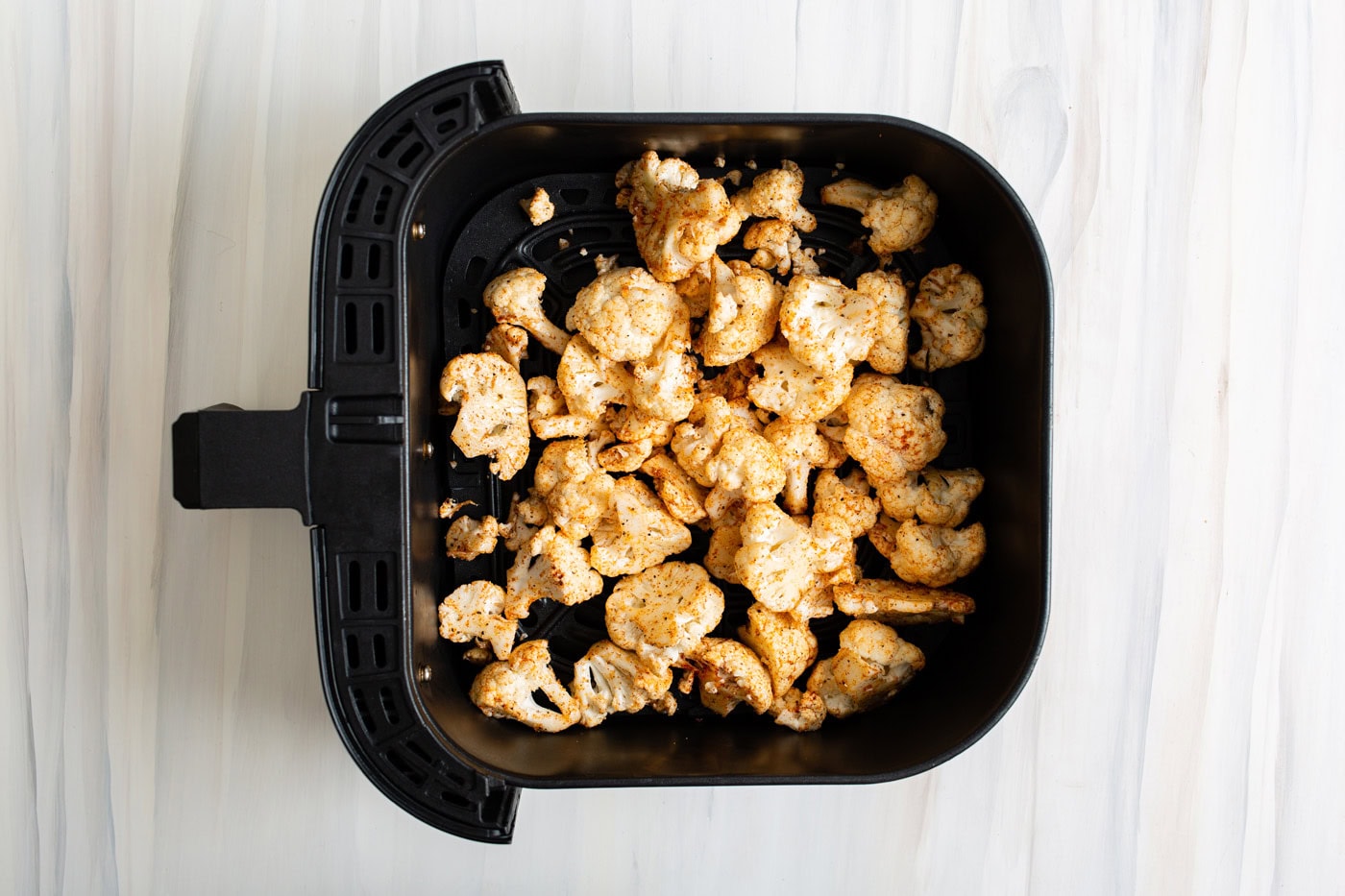 Seasoned cauliflower in an air fryer basket