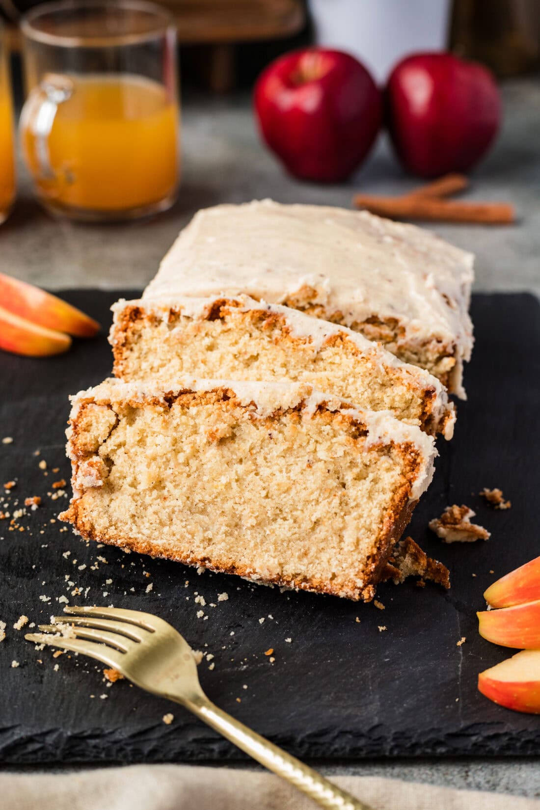 Two slices of Apple Cider Pound Cake resting on the loaf with a fork in front