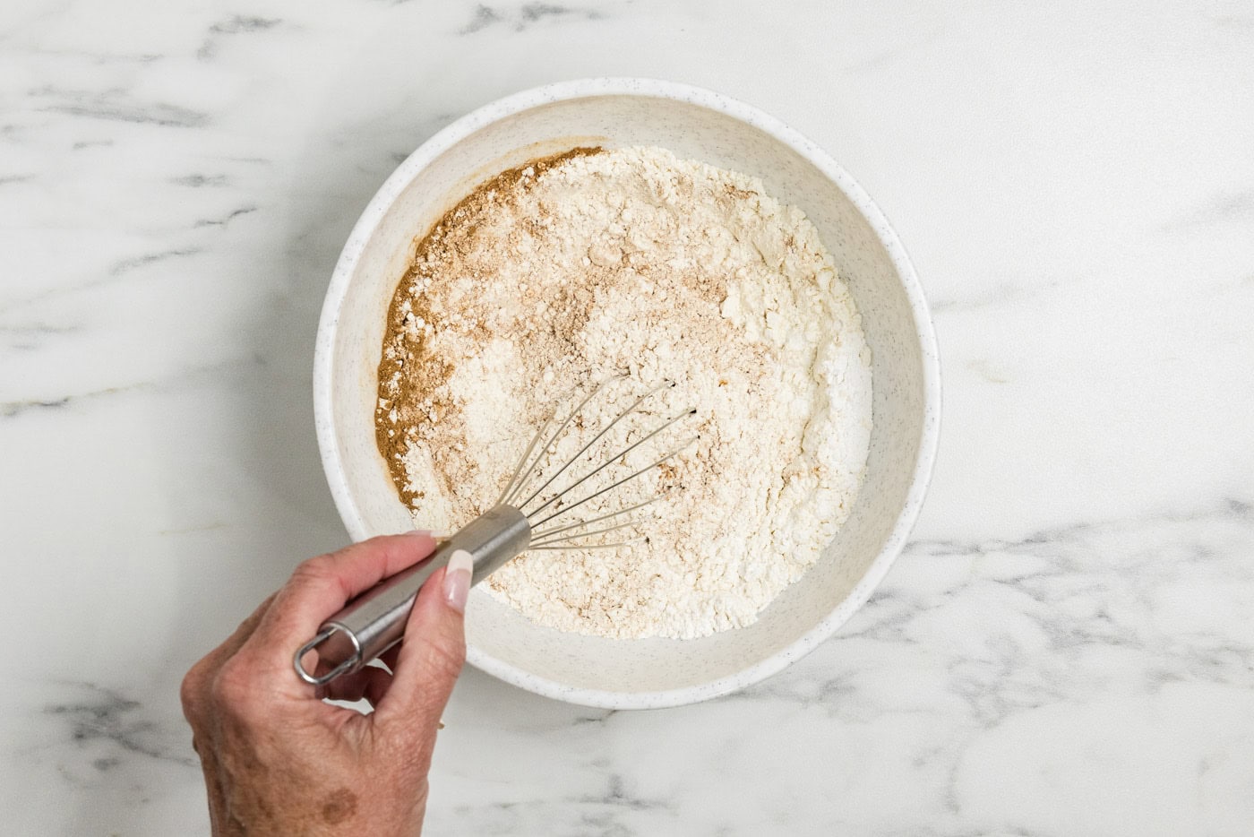 hand whisking dry ingredients in a bowl