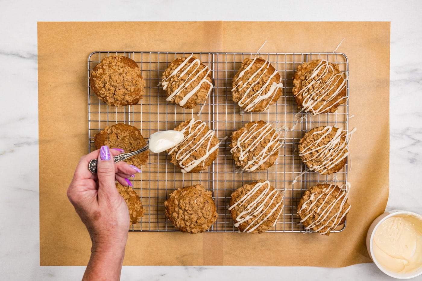 hand drizzling glaze on top of apple streusel muffins