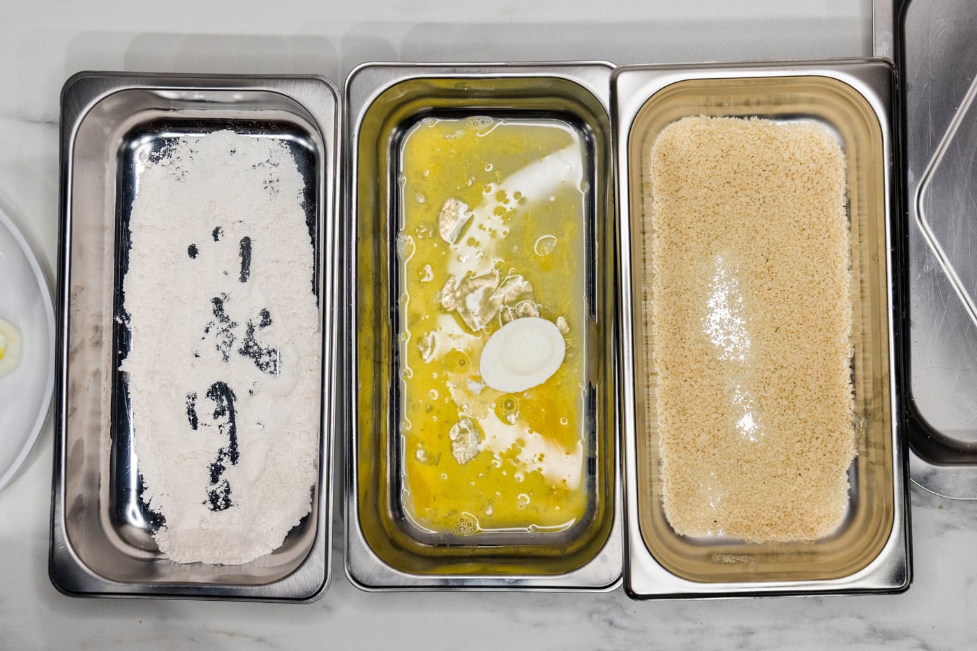 floured egg white dropped into egg wash in a breading tray