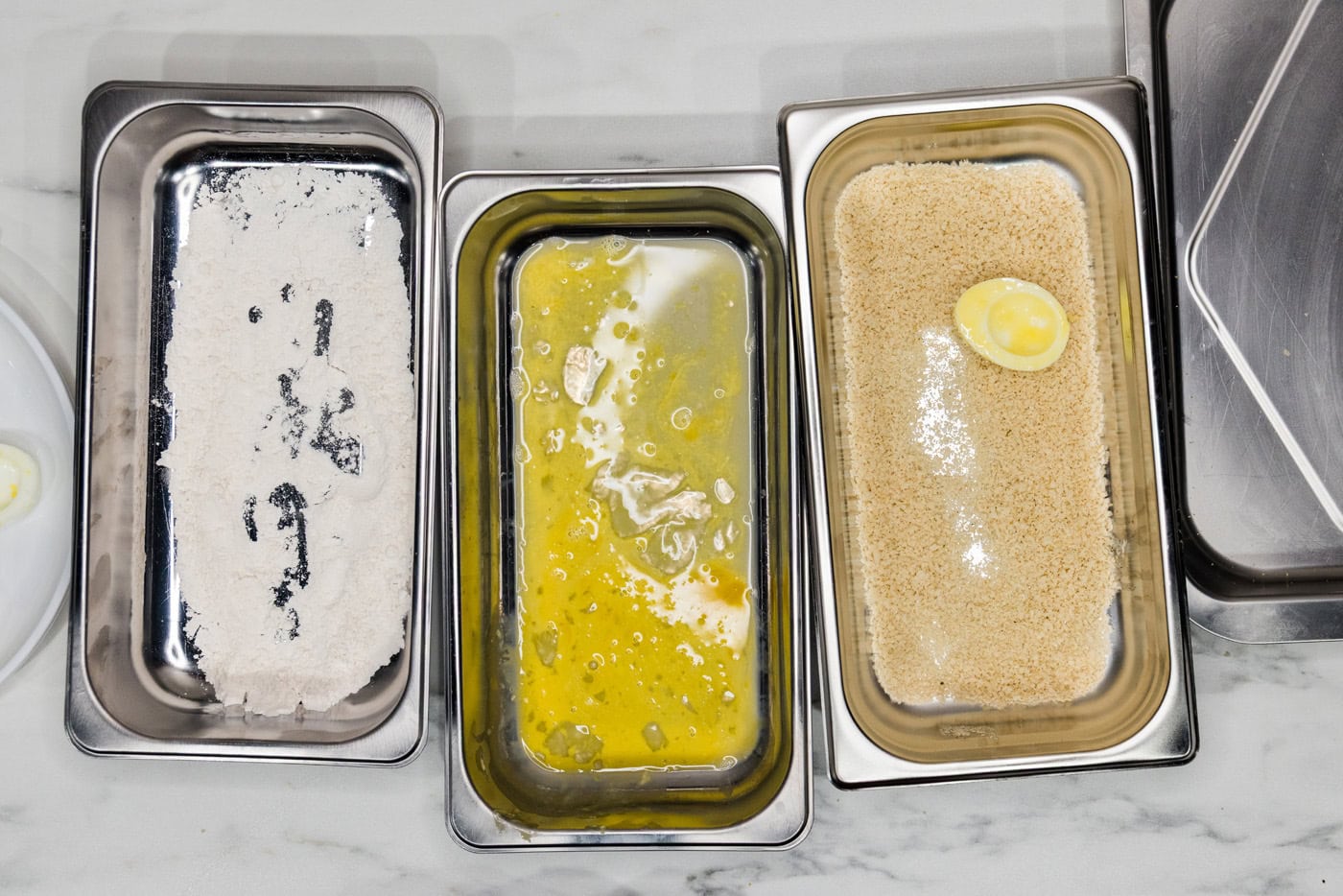 floured and dredged egg white in panko breadcrumbs inside a breading tray