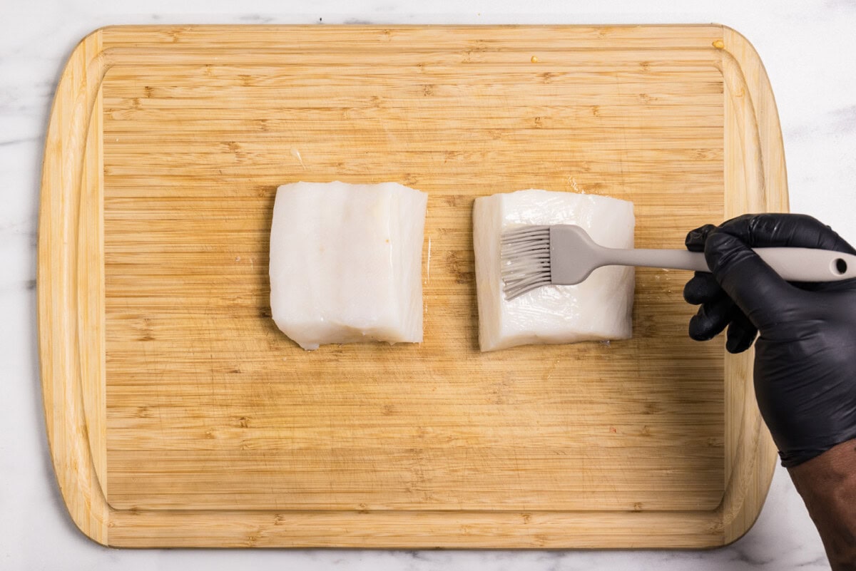 basting brush brushing melted butter onto chilean sea bass filets