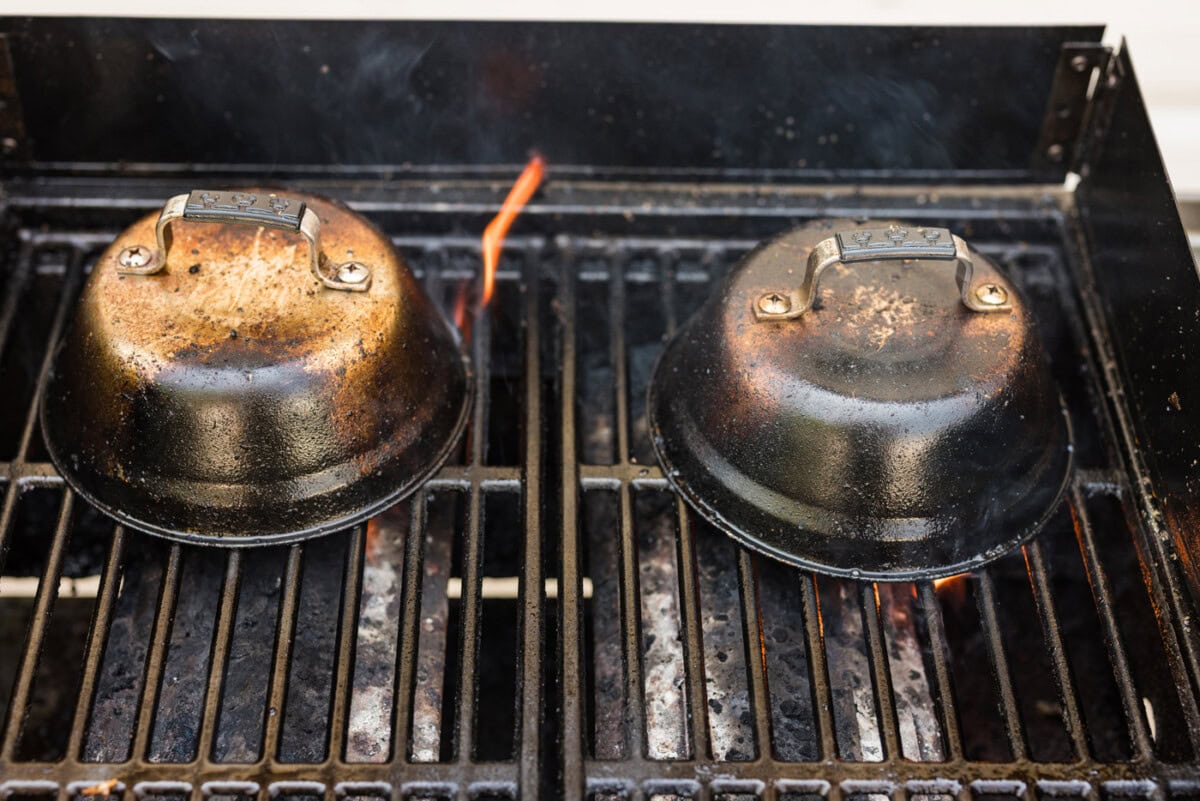 metal basting covers on top of chilean sea bass filets on a hot grill