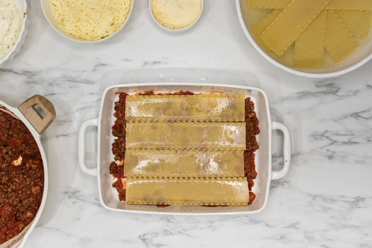 soaked lasagna noodles placed over top of meat mixture in a casserole dish
