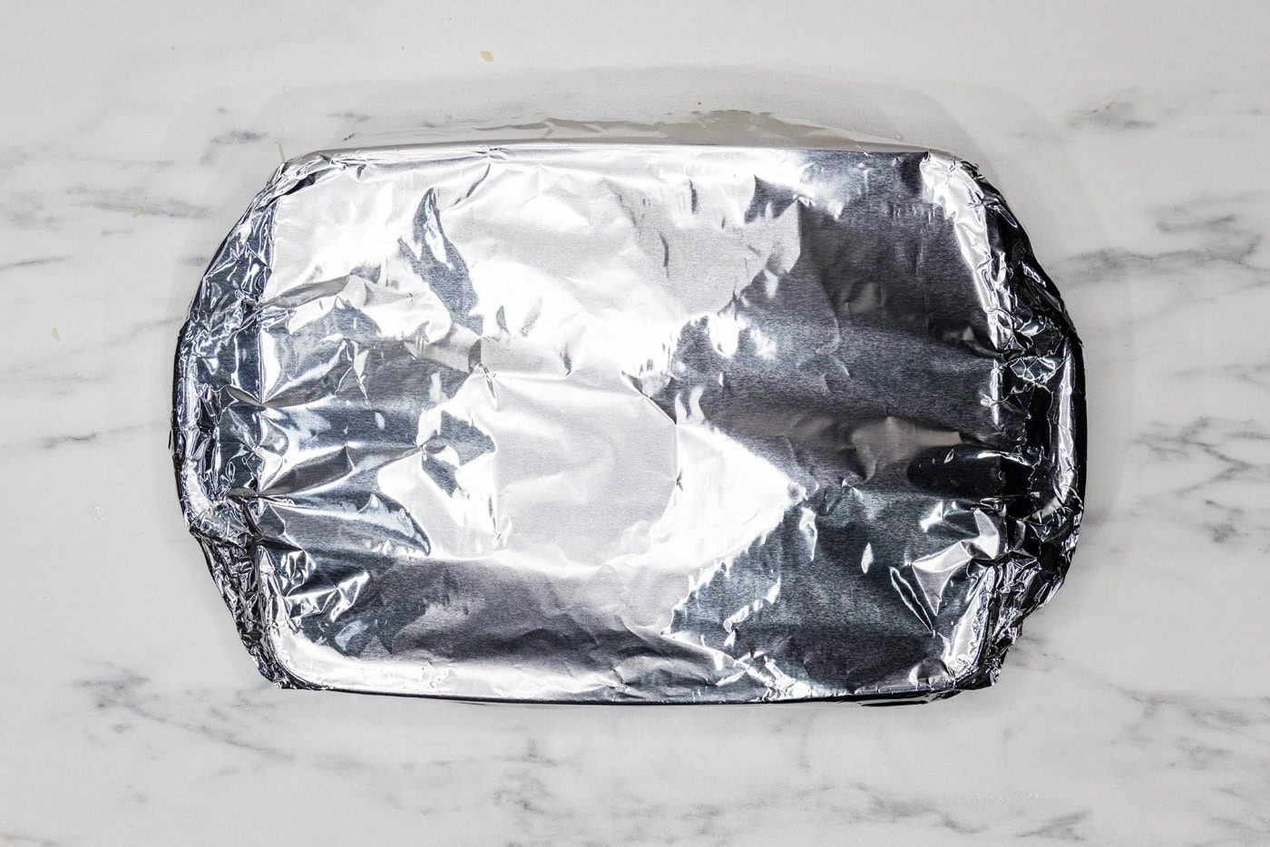 overhead photo of lasagna baking dish covered with aluminum foil