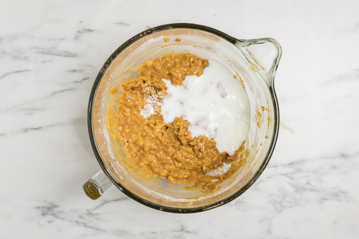 buttermilk added to bowl of pumpkin banana muffin mixture