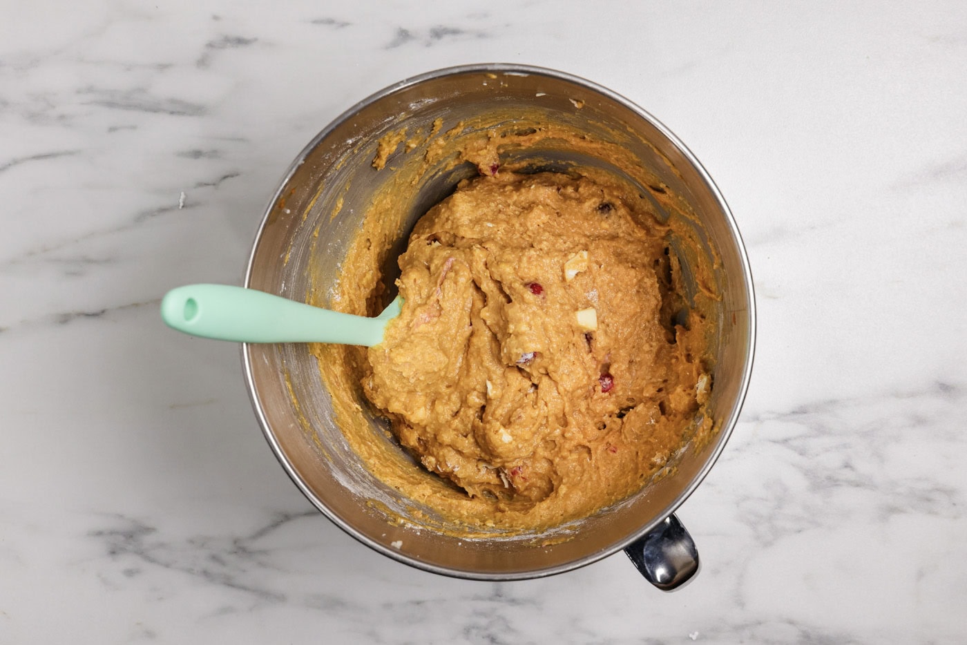rubber spatula in a bowl of pumpkin and cranberry white chocolate muffins