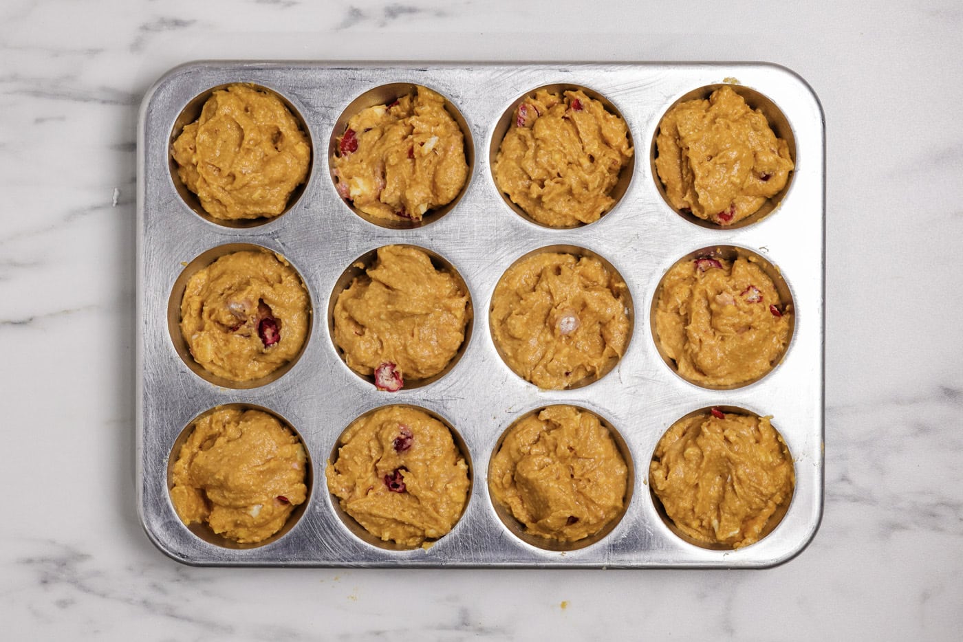pumpkin cranberry muffins batter in a muffin pan